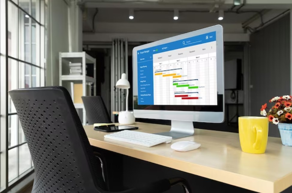 a modern office room with a chair, table, yellow, cup, and PC monitor