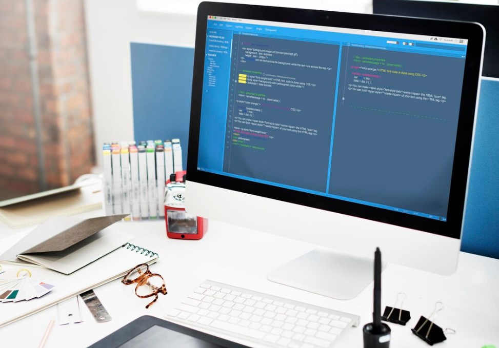 a table with a PC monitor and various office accessories on it