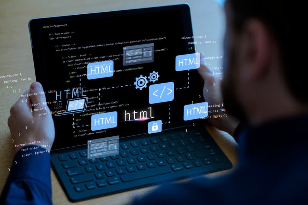 A programmer codes on a laptop with HTML and CSS on screen