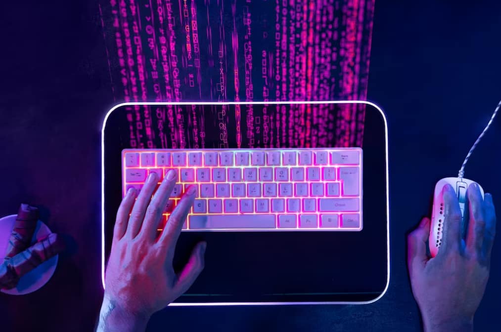 Top-down view of hands typing on a colorful backlit keyboard with digital code overlay