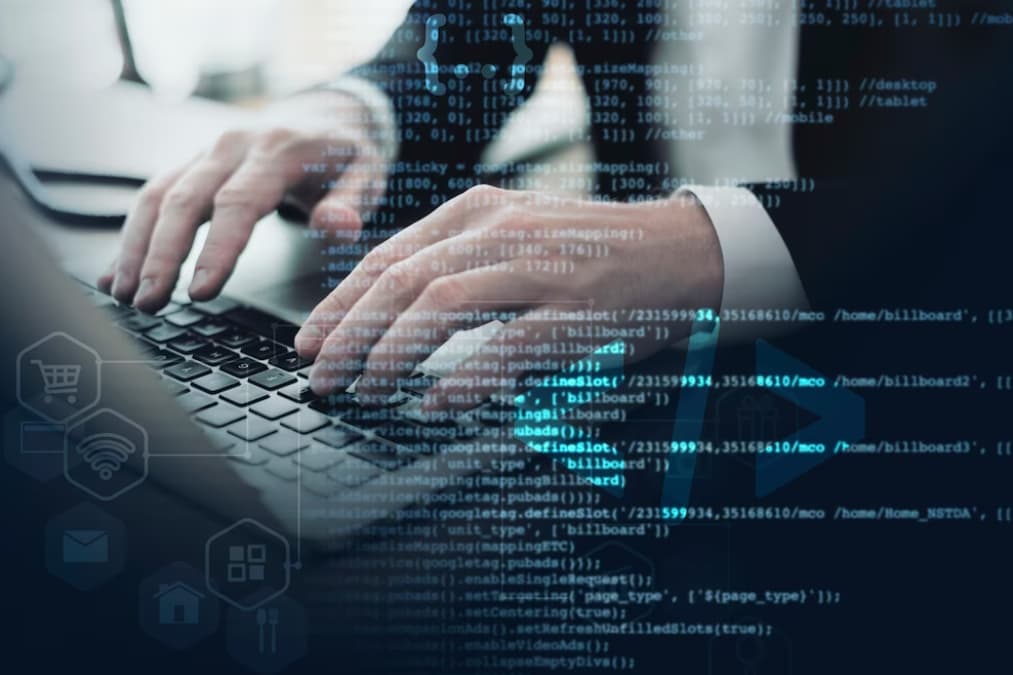 Hands typing on a laptop with code and digital icons overlay